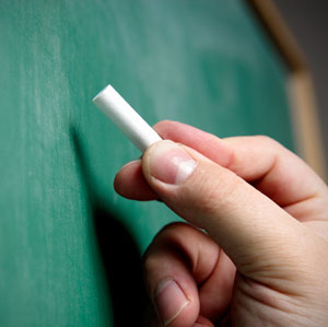 A person writing with chalk against a chalkboard